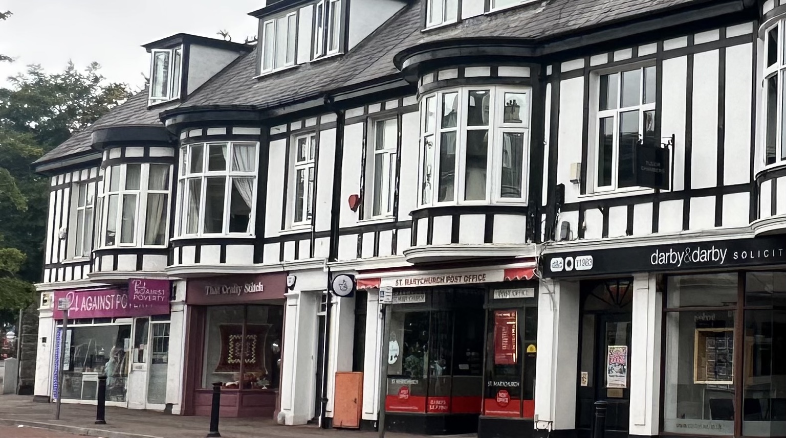 Independent shops and St Marychurch Post Office beneath the black-and-white Tudor Buildings on Fore Street.